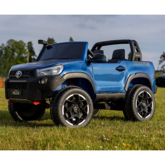 Blue toy truck on grass with trees in the background