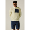 A man wearing a cream-colored quarter-zip fleece pullover with a navy chest pocket and matching navy cargo shorts, standing against a neutral beige background.