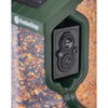Close-up of a Featherpaw bird feeder camera mounted on a dark green feeder frame, with seed containers visible behind it.