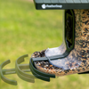 Close-up of a feederSnap bird feeder filled with mixed seed outdoors, with a green grassy background and the feederSnap logo visible on the top.