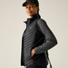 Person wearing a black quilted jacket and cap on a plain background
