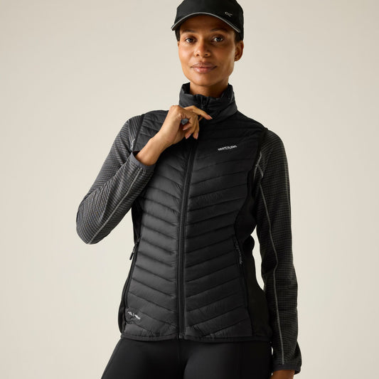 Person wearing a black quilted jacket and cap on a plain background