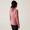 Person wearing a pink quilted jacket and black beanie on a plain background