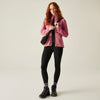 Woman wearing a pink jacket, black leggings, and black boots on a light gray background