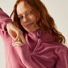 Woman wearing a pink fleece jacket with a brand logo on a neutral background