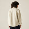 Person wearing a cream-colored sweater against a plain background