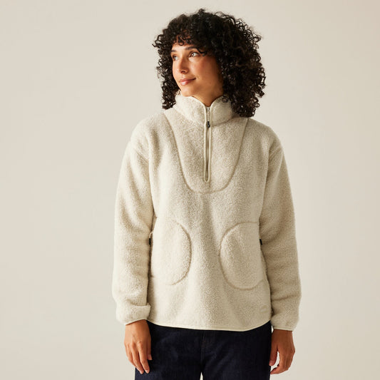 Person wearing a beige fleece pullover with a zipper on a plain background