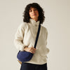 Person wearing a cream fleece jacket holding a blue bag against a plain background