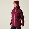 Person wearing a maroon jacket and matching beanie on a beige background