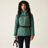 Woman wearing a green jacket with a backpack on a plain background