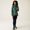 Woman wearing a green jacket, gray shirt, black leggings, and hiking boots on a white background
