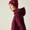 Person wearing a maroon jacket and beanie on a beige background