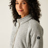 Woman wearing a gray fleece jacket with a brand logo on a plain background