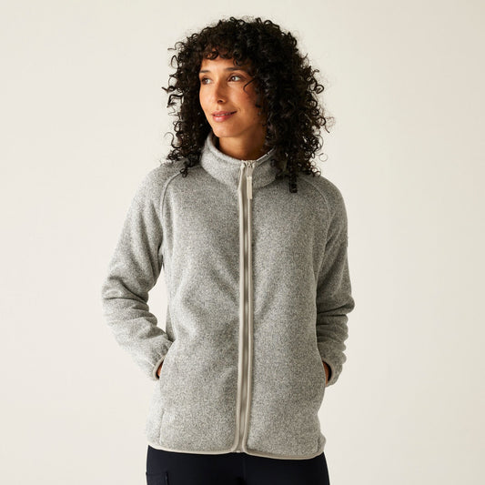 Woman wearing a gray zip-up hoodie against a plain background