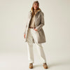 Person wearing a beige coat, white pants, and brown boots on a plain background