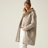 Woman wearing a beige parka and beanie on a plain background