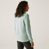 Woman wearing a light green turtleneck sweater against a white background