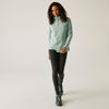 Woman wearing a light green pullover and black leggings on a white background