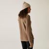 Woman wearing a beige sweater and knit beanie against a plain background