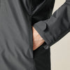 Close-up of a person wearing a black jacket with a beige background