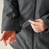 Person adjusting the cuffs of a dark gray jacket with a brand logo.