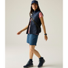 a woman wearing  navy cap, shoes, socks and shorts, with a navy andreson gilet puffer and a pink tshirt underneath with a navy cross body bag