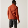 a man wearing a brick red fleece facing backwards, with grey shorts on an offwhite background