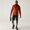a man wearing a brick red fleece with a halfzipper in grey shorts, holding a waterbottle, wearing black and orange mountain boots on an offwhite background