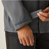 Close-up of a person wearing a dark gray waterproof jacket, demonstrating the cuff feature with a hook-and-loop strap. The brand name is printed in white on the sleeve.