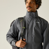 a man wearing a grey rainjacket with a backpack over his right shoulder