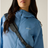 a woman wearing a blue jacket on beige background with black bag and brown shorts