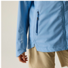 a woman wearing a blue jacket on beige background with black bag and brown shorts