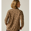 A woman shown from the back wearing a leopard-print fleece pullover. The garment has a tan base with dark brown and black leopard spots, photographed against a solid light gray studio background.