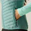 Close-up of a person wearing a light aqua quilted puffer vest over a matching long-sleeve top, with one hand reaching into a side pocket.