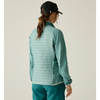 woman facing away from camera with green pants and black cap on off white background