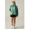 green long sleeve jacket with green tshirt underneath, black skirt and socks, white hat and shoes on woman with off white background