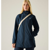 a woman standing wearing a navy rainjacket with a cream bag strap over her shoulder