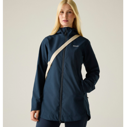 a woman standing wearing a navy rainjacket with a cream bag strap over her shoulder