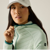 A close-up of a woman wearing a dual-layer hooded jacket, featuring a navy blue outer shell and a blue quilted puffer lining. The brand logo is visible on the chest.