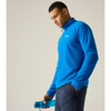 A man wearing a bright blue long-sleeve quarter-zip fleece pullover and dark gray pants, holding a matching blue water bottle against a plain light gray studio background.