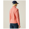 A woman shown from the back wearing a coral pink fleece jacket, navy blue leggings, and a navy blue baseball cap, set against a solid light beige background.