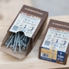Two boxes of RAWPLUG wood screws on a light wood surface, with one open box showing silver metal screws inside and the other box standing beside it.