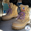 A beige tactical-style lace-up boot with purple laces, a side zipper, and a Steel Blue logo patch on the tongue, shown against a plain white background.